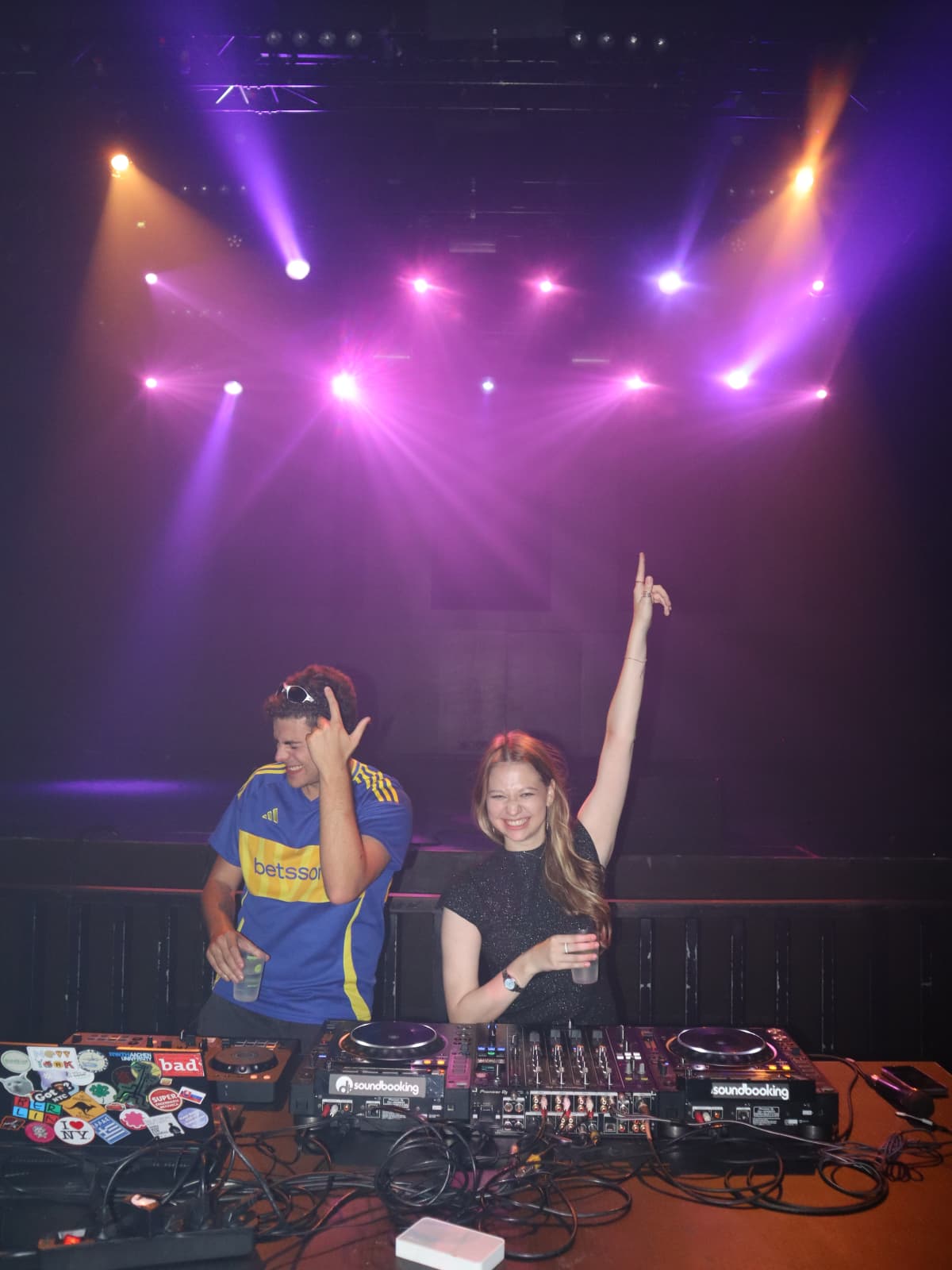 Dois estudantes na cabine de DJ sob as luzes de palco numa festa da ESN Porto