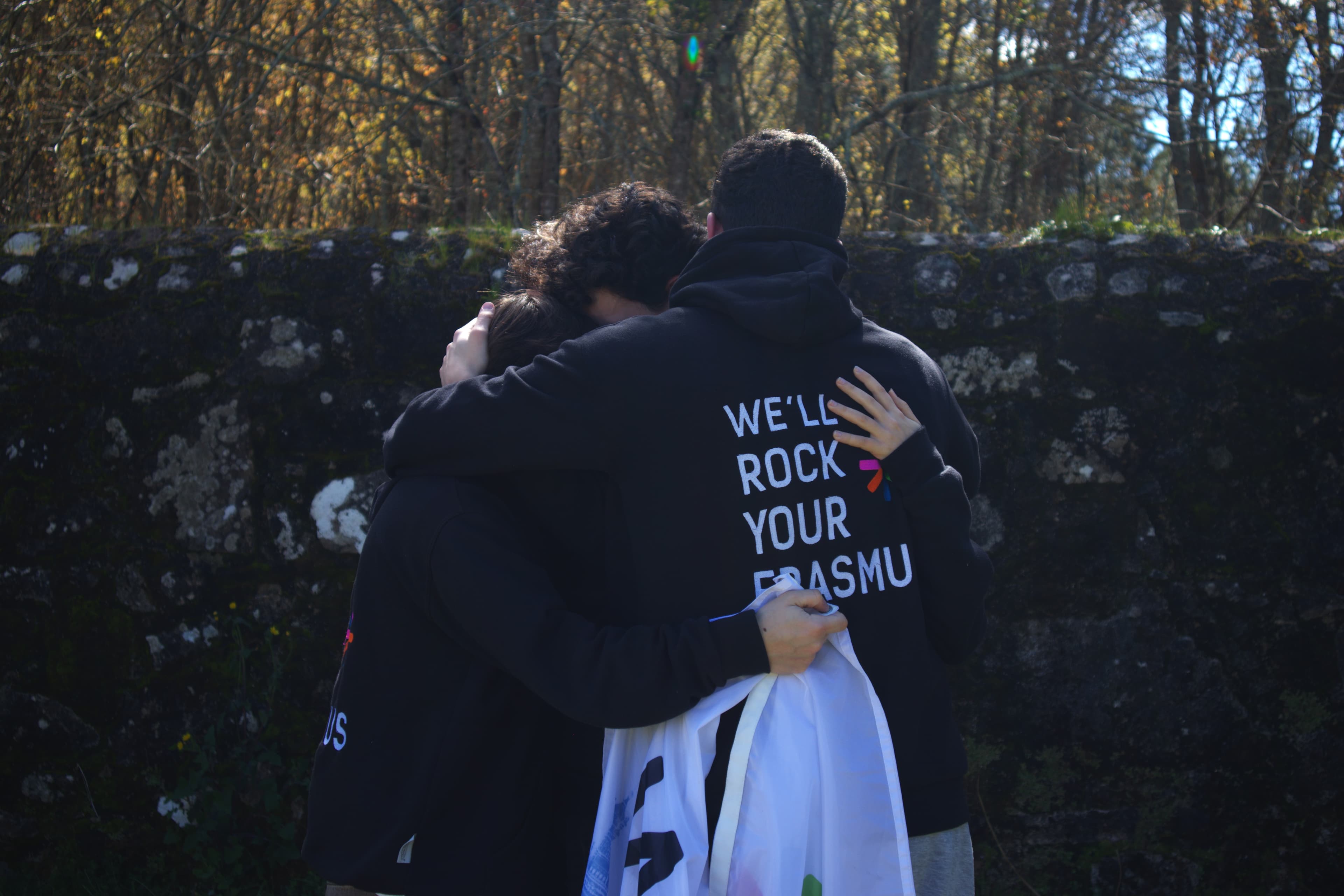 Three ESN Porto volunteers seen from behind, arms around each other, wearing ESN hoodies